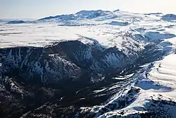 A rocky canyon cut into a snow-covered plateau