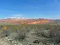 A photo of the Red Cliffs with snow-capped Pine Valley Mountains in the background