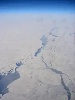 Aerial view of the Chukchi Sea between Chukotka and Alaska, displaying a pattern of leads. Much of the open water inside those leads is already covered by new ice (indicated by a slightly lighter blue color)(scale not available).