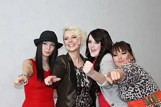 A shot of four women looking at the camera in front of a white backdrop.