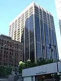 Ground-level view of a 20-story building with prominent black windows and a white, concrete facade
