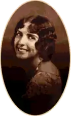 A studio photograph of a young woman looking over her shoulder.