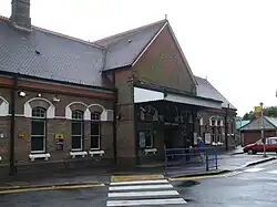 A brown-bricked building with a rectangular, dark blue sign reading "RUISLIP STATION" in white letters all under a clear, white sky