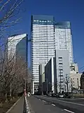 Ground-level view of a three-building complex; each building is white and blue and lined with rows of windows